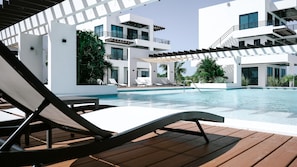 Relax by the pool surrounded by lounge chairs and umbrellas, with a clear view of the surrounding area.