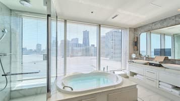 A modern bathroom with a large bathtub, a double sink vanity, and a large mirror.