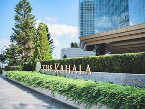 A sign for 'The Kahala Hotel & Resort' with a modern building in the background.