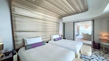 A hotel room with two beds, a small seating area, and a view of the balcony.