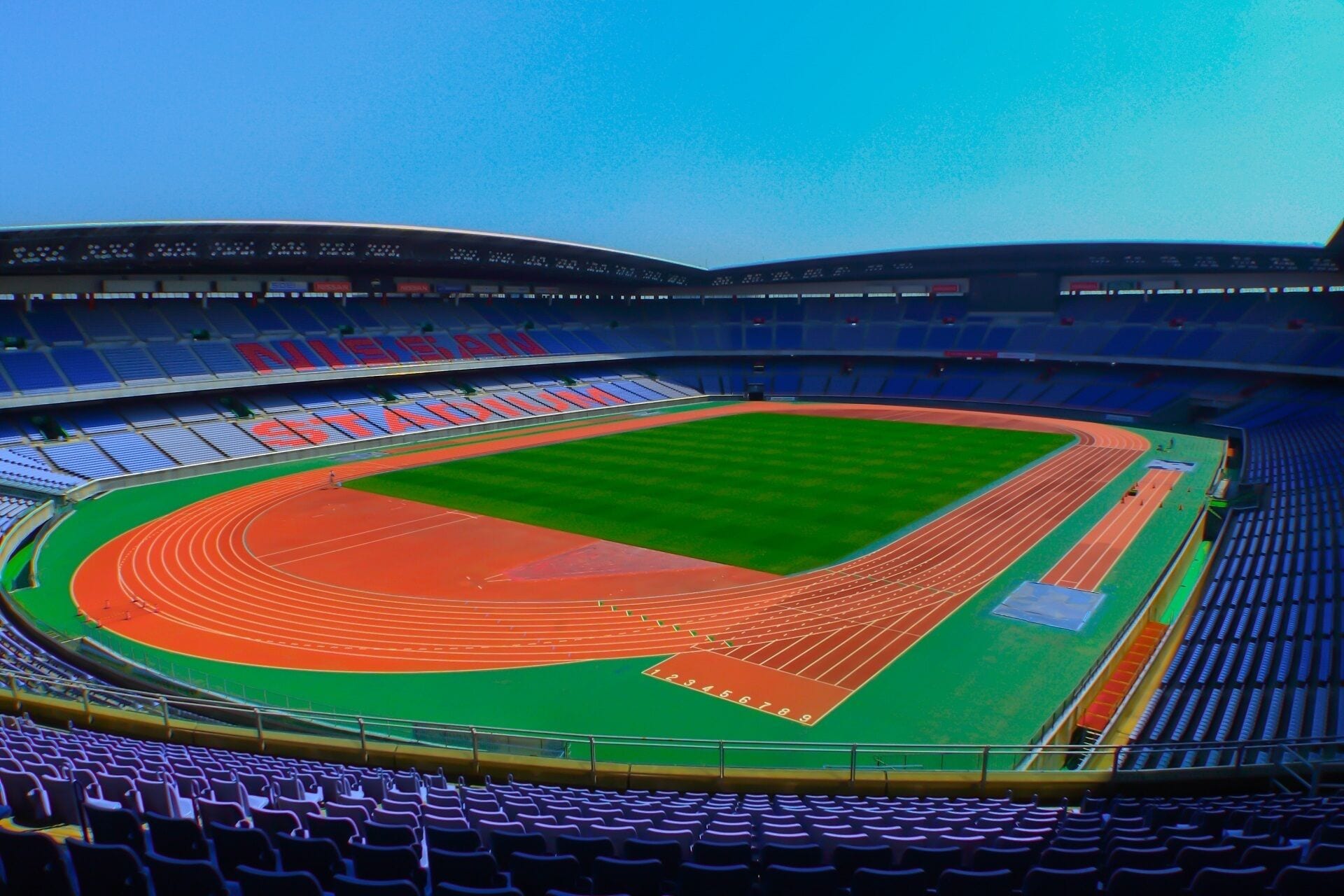 Ein Stadion mit mehreren Sitzreihen, einer Laufbahn in der Mitte und einem grünen Rasen.