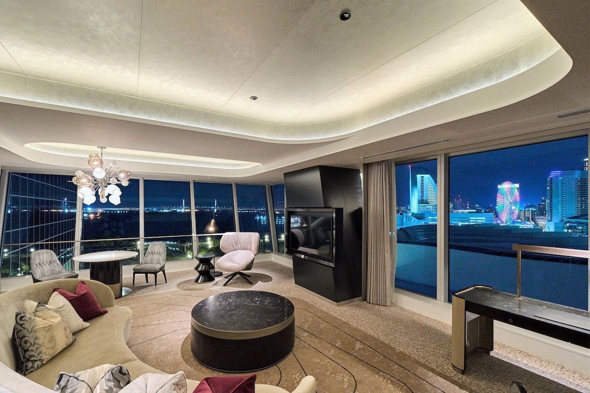 Ein modernes Wohnzimmer mit gewölbter Decke, einer Couch, einem Fernseher und Blick auf eine nächtliche Skyline.