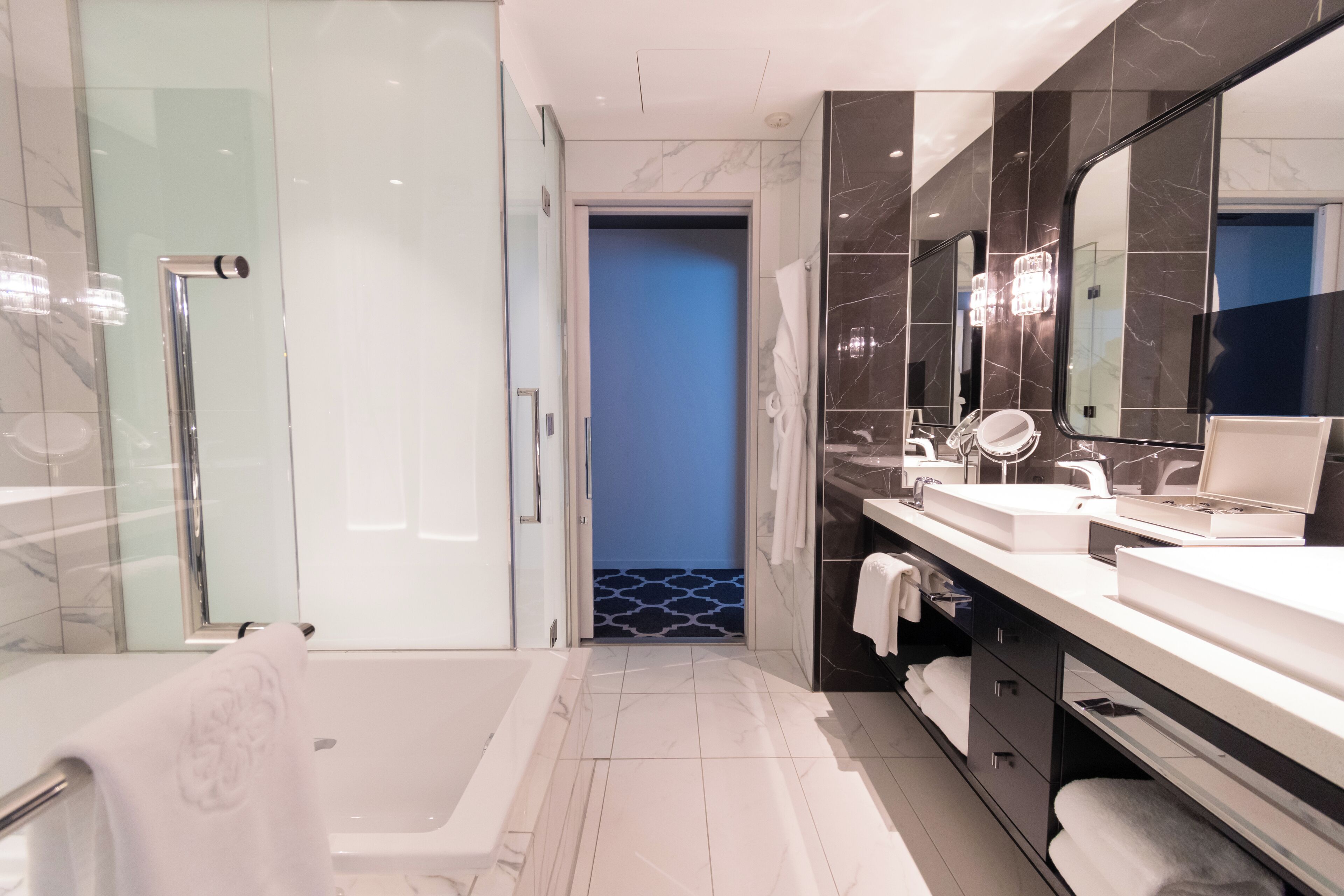 Un baño moderno con cabina de ducha de vidrio, bañera tipo jacuzzi y tocador con un espejo grande.
