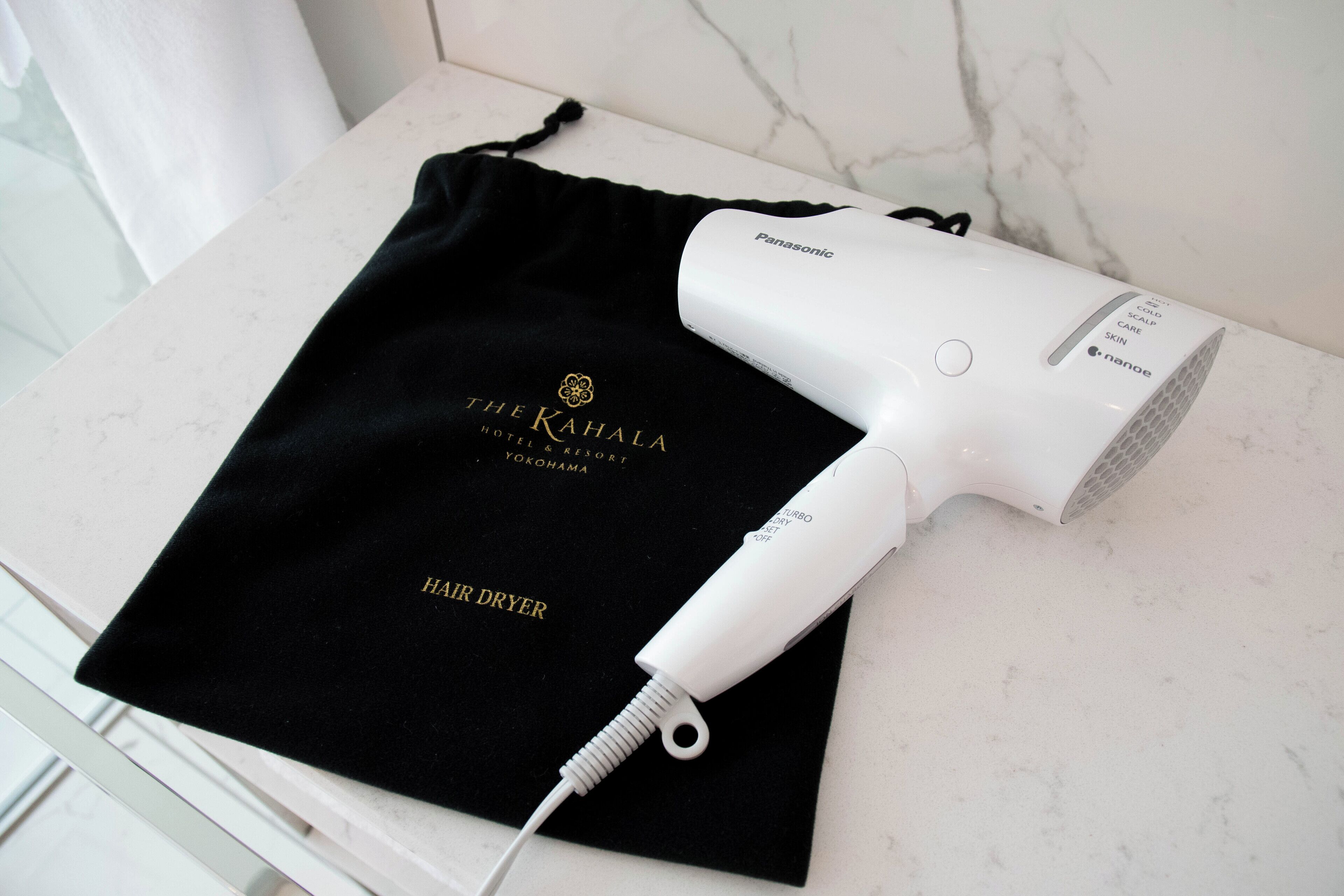 A Panasonic hair dryer on a white marble countertop with a black cloth underneath.