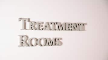 Een bord met de tekst 'TREATMENT ROOMS' in een Serif lettertype, op een witte achtergrond.