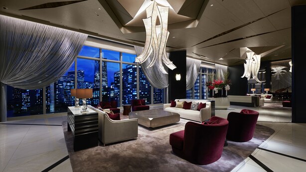 A modern hotel lobby with a city view, a large chandelier, and contemporary furniture.