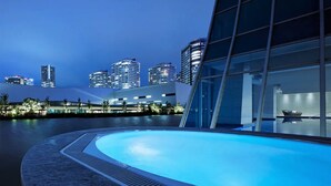 A modern building with a pool, surrounded by high-rise buildings.