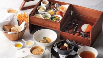 A variety of food items and beverages arranged on a marble surface, including bread, soup, and a tea cup.