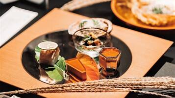 A table with a dessert plate, a glass of a clear liquid, and a small dish with a green garnish.