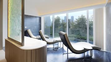 Ein moderner Empfangsbereich mit einer gebogenen Rezeption, zwei Lounge-Sesseln und einem großen Fenster mit Blick auf Stadt und Grünflächen.
