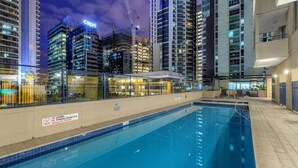 Ein Schwimmbecken mit Blick auf hohe Gebäude und Baukräne im Hintergrund.