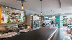 Eine Bar mit einer langen Theke, Regalen voller Flaschen und hängenden Lampen.