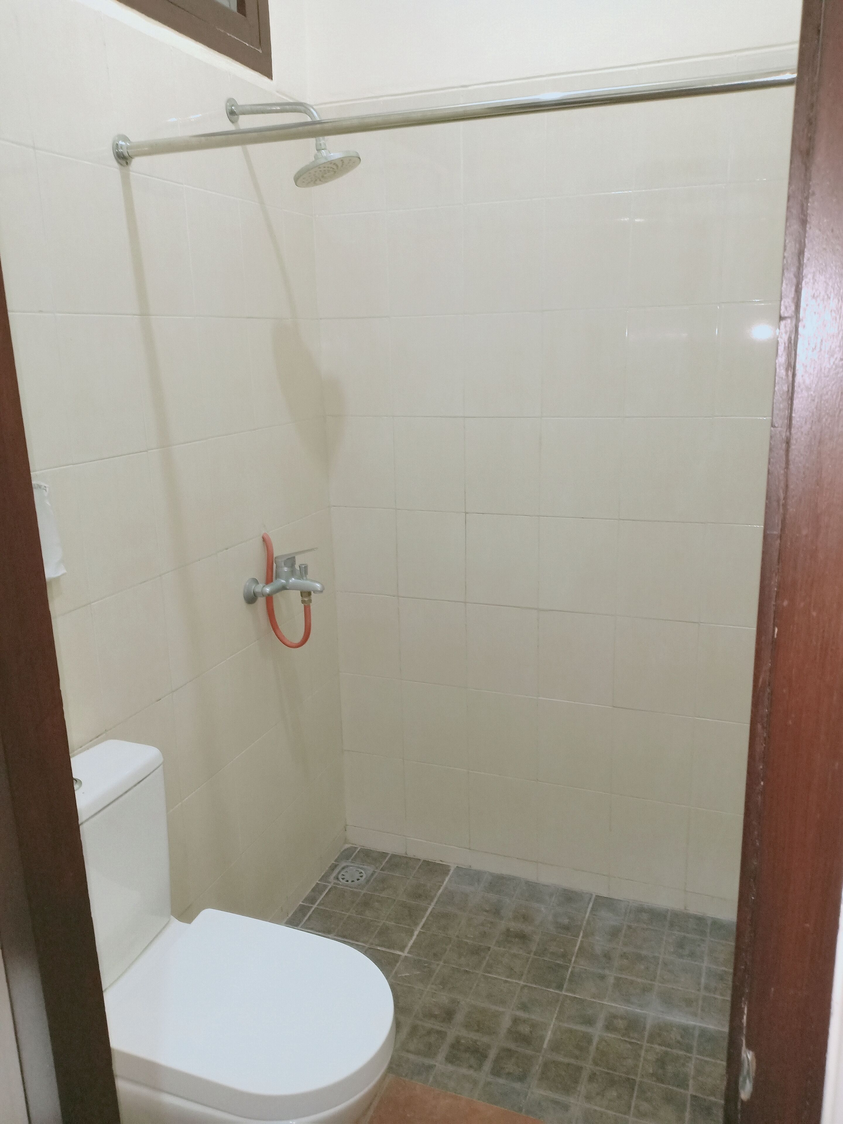Et aflukket bruseområde med toilet og brusehoved.