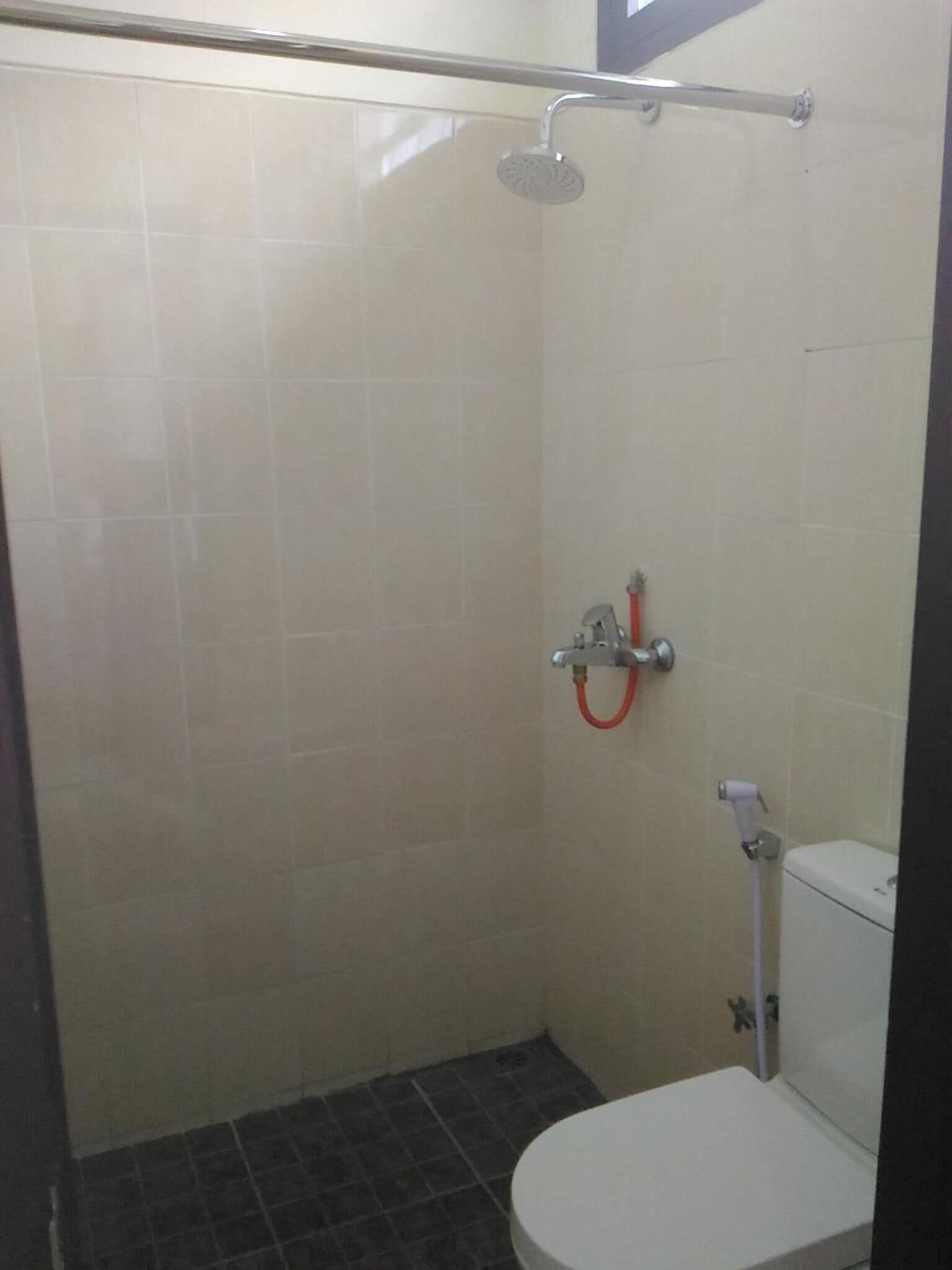 A small, enclosed shower area with a toilet and a showerhead.