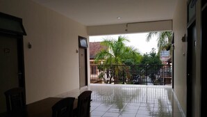 A clean, tiled balcony with a view of palm trees and a residential area. - K15 Exclusive (Malang)