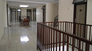A hallway with a dining area, a staircase, and a door marked with the number 218. - K15 Exclusive (Malang)