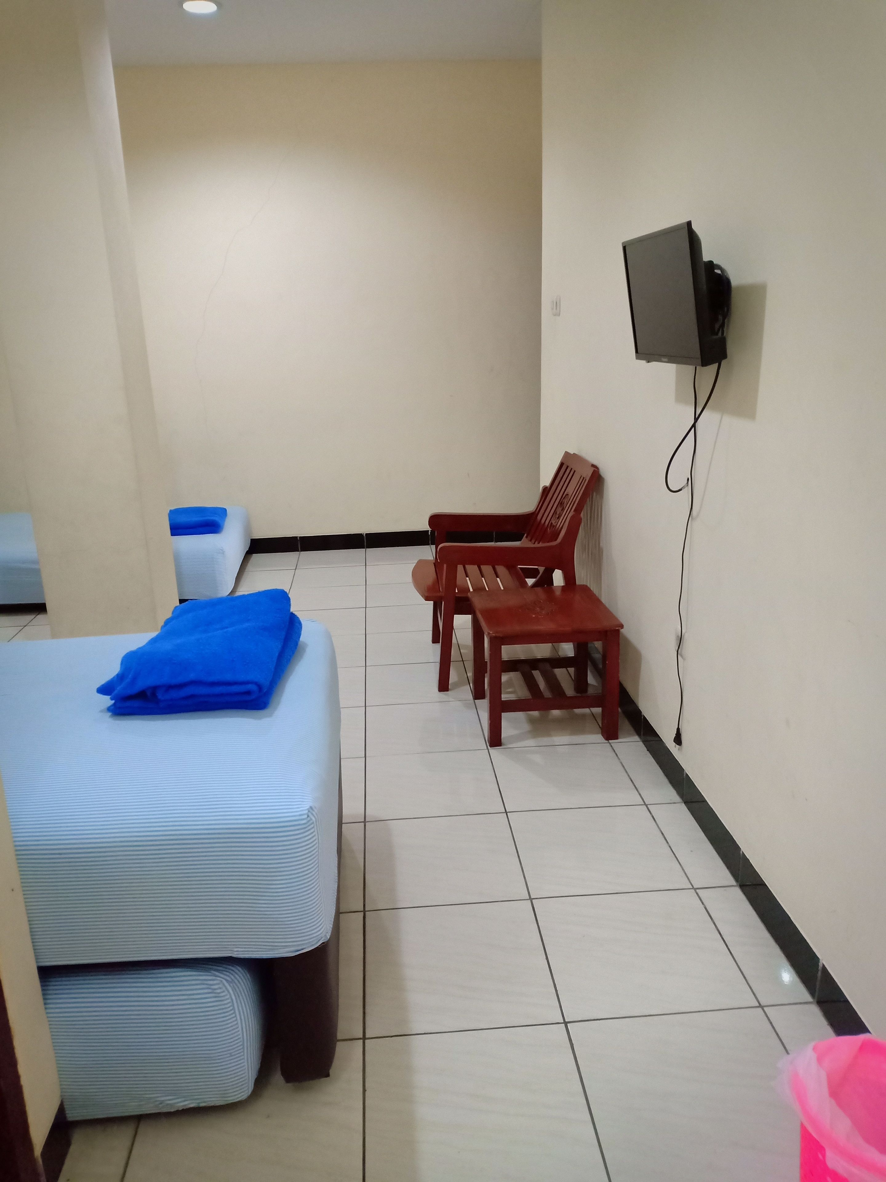 Una habitación de hotel con una cama, un televisor montado en la pared y un pequeño juego de mesa y silla.