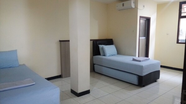 A bedroom with a bed, a sofa bed, and a small table. - K15 Exclusive (Malang)