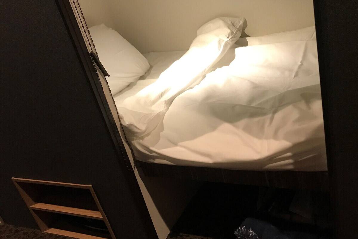 A bunk bed with white bedding and a wooden ladder.
