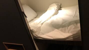 A bunk bed with white bedding and a wooden ladder.