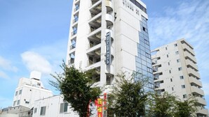 Un hotel de varios pisos con un diseño moderno, que cuenta con balcones en cada planta y un llamativo frente de vidrio.
