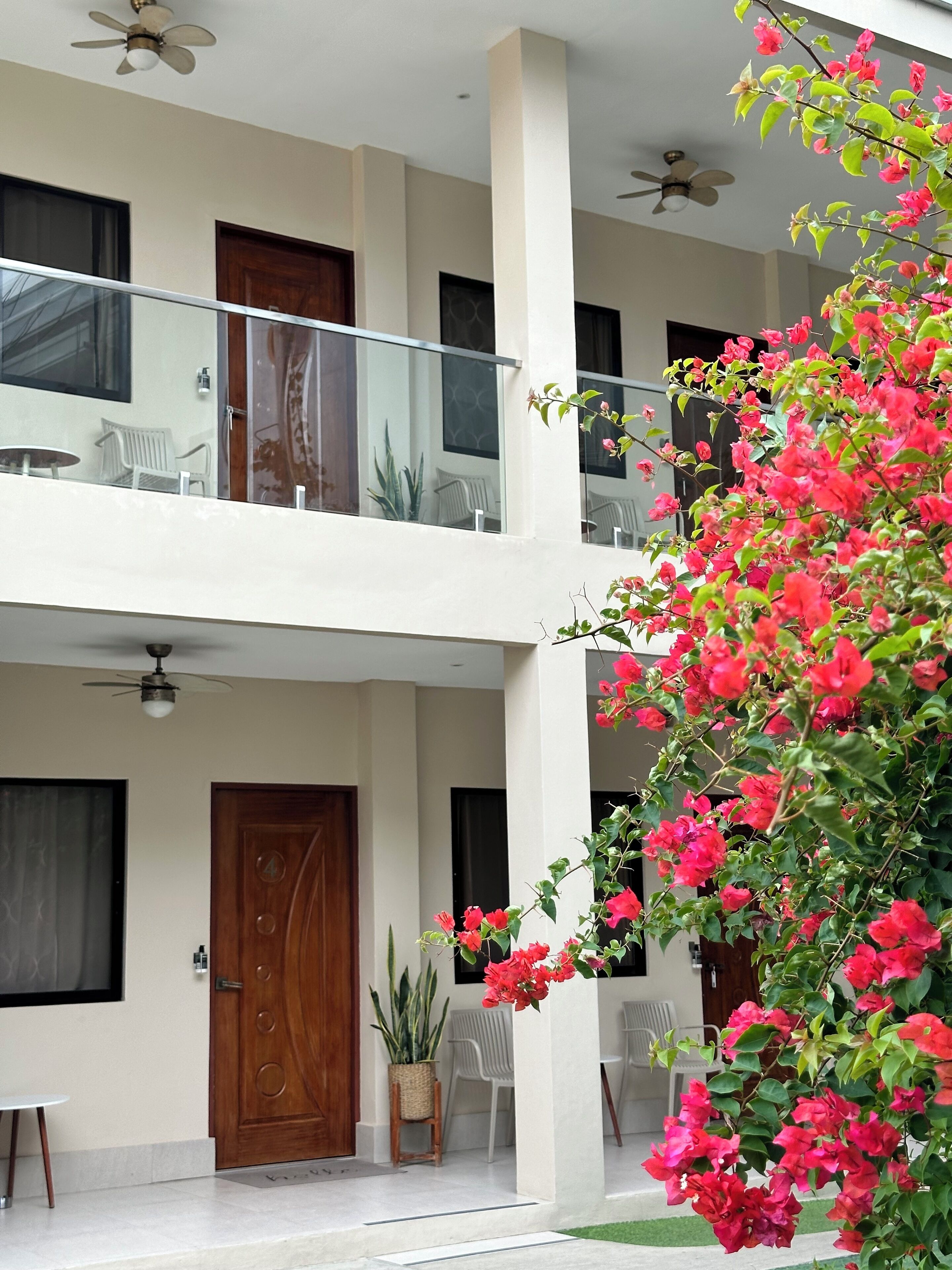 A two-story building with a balcony, a wooden door, and a potted plant.