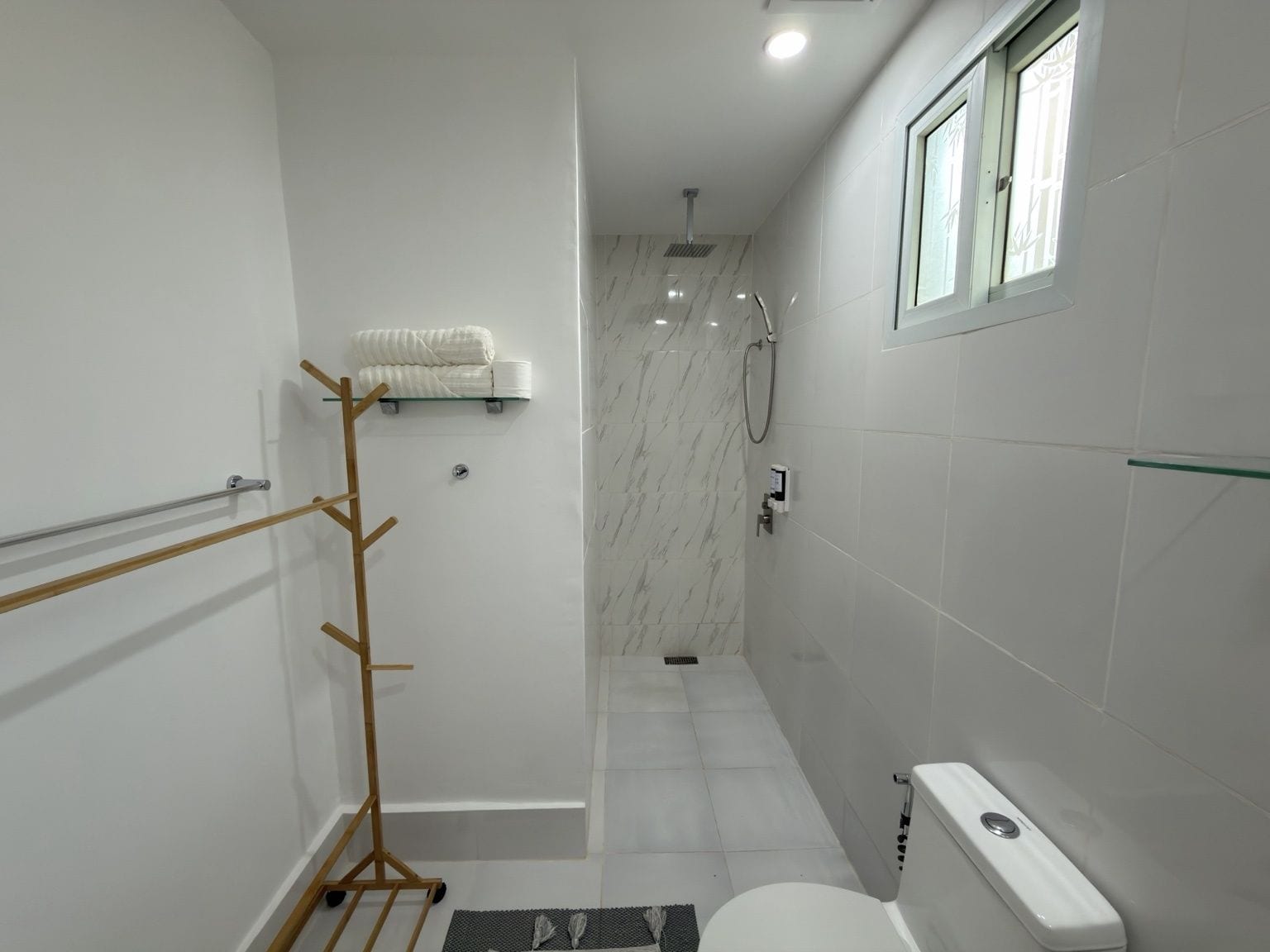A modern bathroom with a glass shower enclosure, a toilet, and a towel rack.