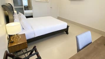 A hotel room with a bed, a desk, a chair, a TV, and a painting on the wall.