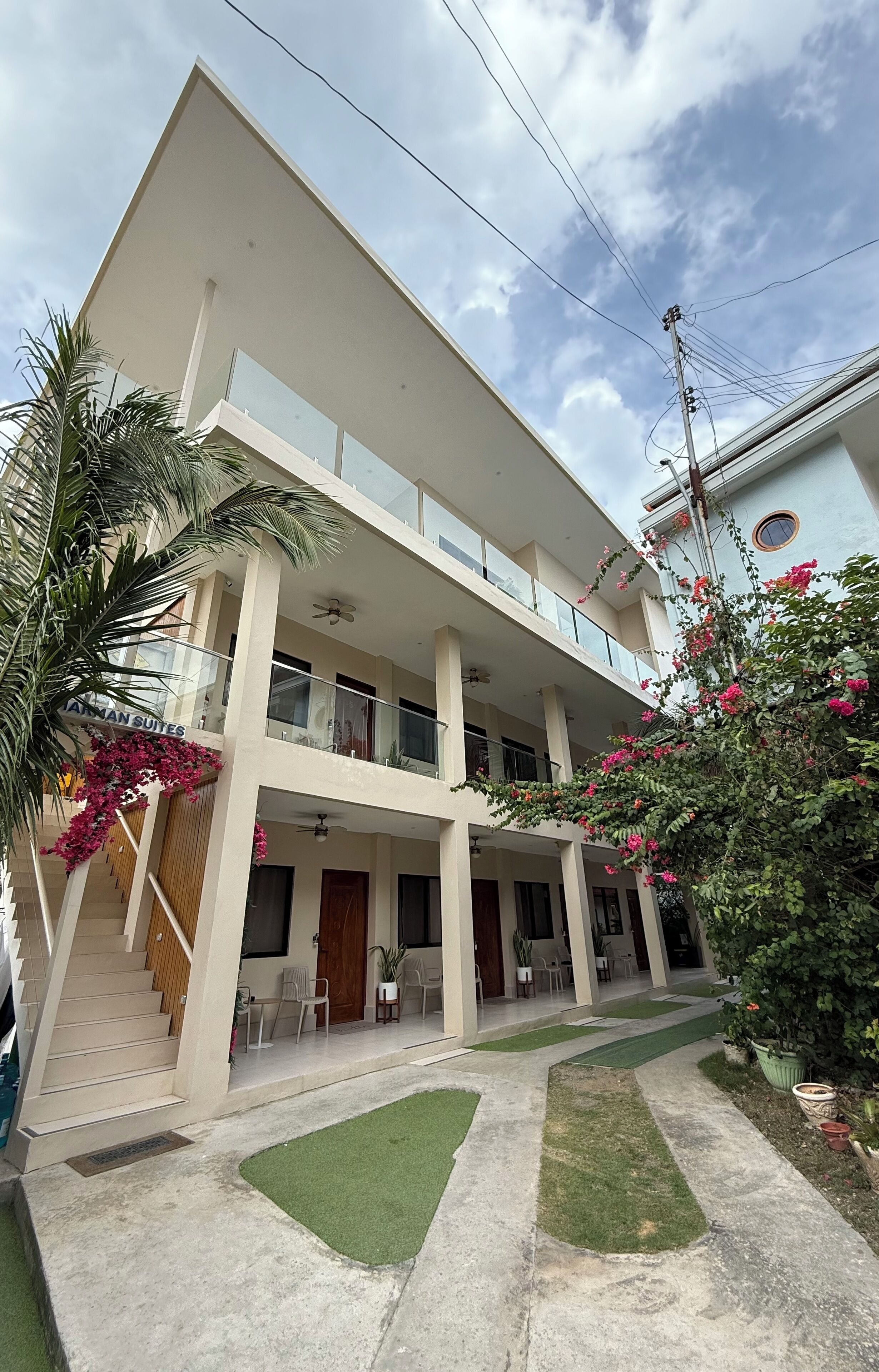 A two-story building with a flat roof, multiple balconies, and a sign indicating "JAMAN SUITES."