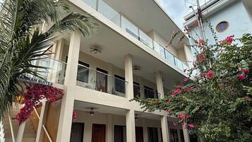 A two-story building with a flat roof, multiple balconies, and a sign indicating "JAMAN SUITES."
