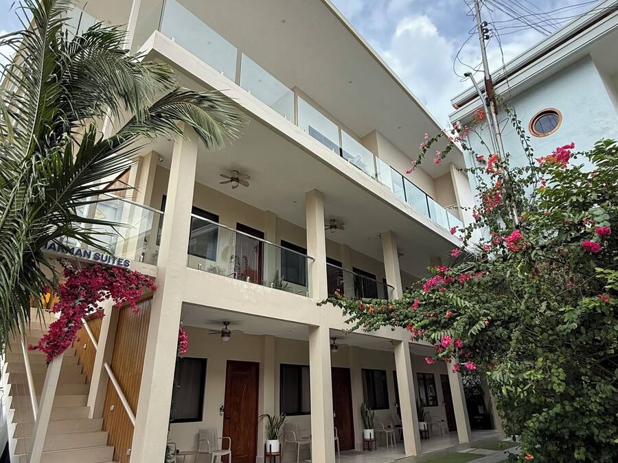 A two-story building with a flat roof, multiple balconies, and a sign indicating "JAMAN SUITES."