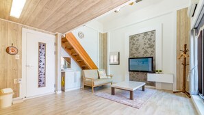 Een moderne woonkamer met een houten trap, een bank, een salontafel en een televisie.
