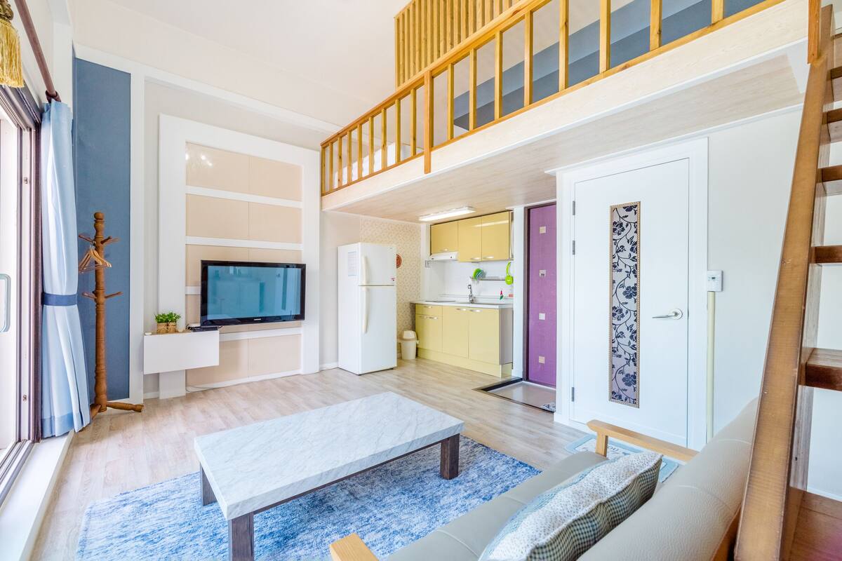 Una sala moderna con televisor, sofá y mesa de comedor.