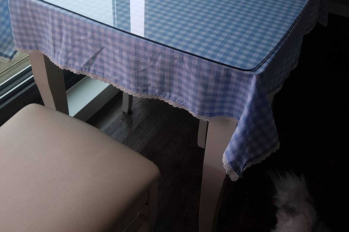 Una mesa de comedor con mantel a cuadros, una silla blanca y un banco.