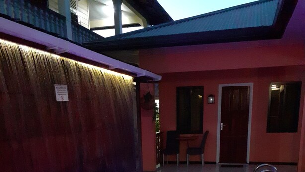 A swimming pool with a purple light, a wooden fence, and a building with a red exterior.