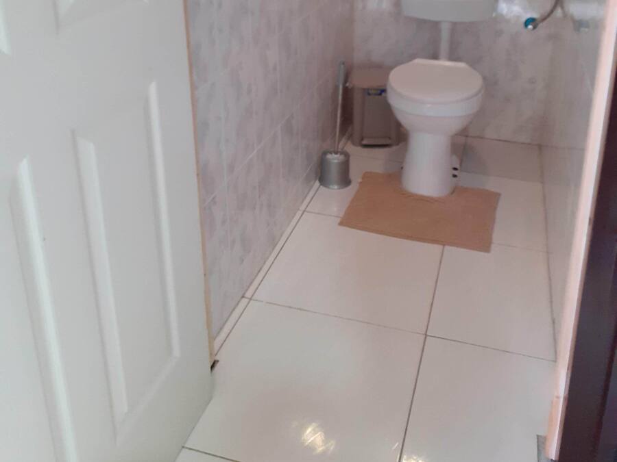 Un baño pequeño y limpio con inodoro, lavamanos y suelo de baldosas.