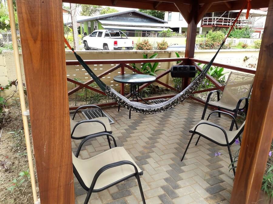 Un porche cubierto con una hamaca, sillas y una mesa.
