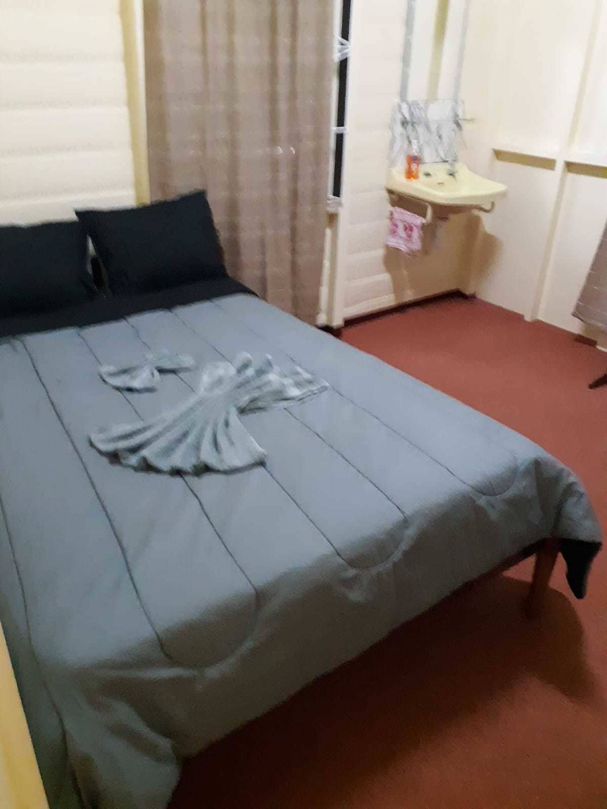 A neatly made bed with a blue bedspread and a white towel arranged on it.