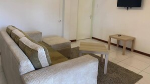 A living room with a sofa, ottoman, and a small table.