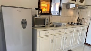 A modern kitchen with white cabinetry, a built-in microwave, a gas stove, and a Whirlpool refrigerator.