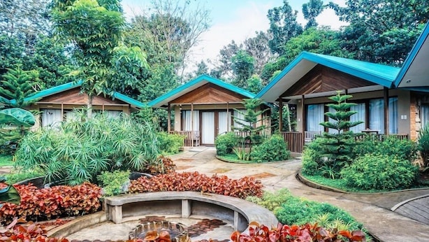 A resort with three wooden-roofed cottages surrounded by lush greenery and a central water feature. - Ted's Bed and Breakfast (Santa Cruz)