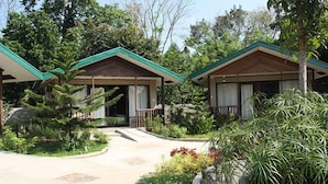 A bungalow-style hotel with a green roof, surrounded by lush greenery and a paved walkway. - Ted's Bed and Breakfast (Santa Cruz)
