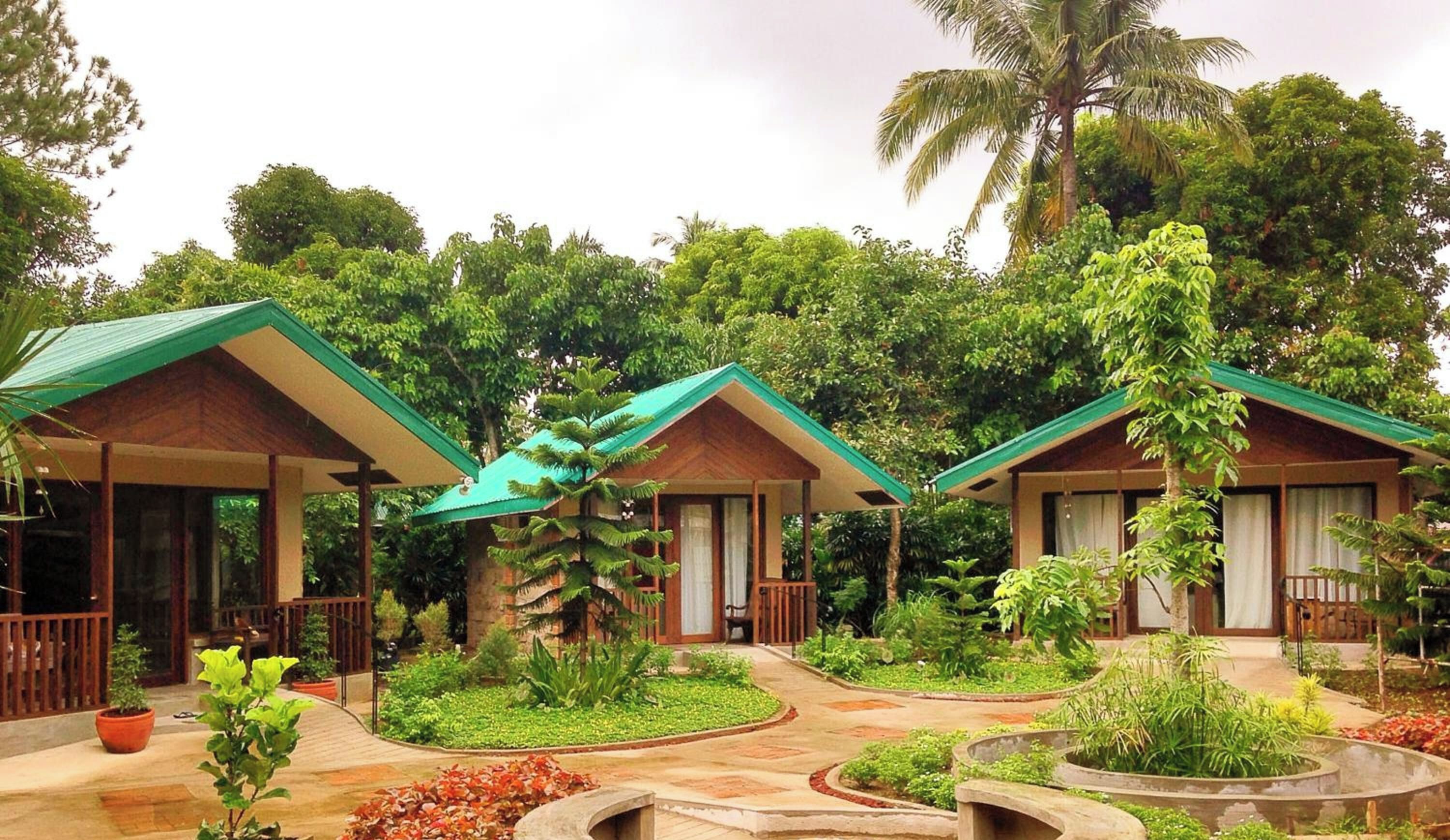Et resort med flere bungalows, hver med veranda og omgivet af frodig vegetation.