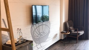 A modern living room with a mounted TV, a comfortable armchair, and a small side table. - Banana Flower Homestay (Da Nang)