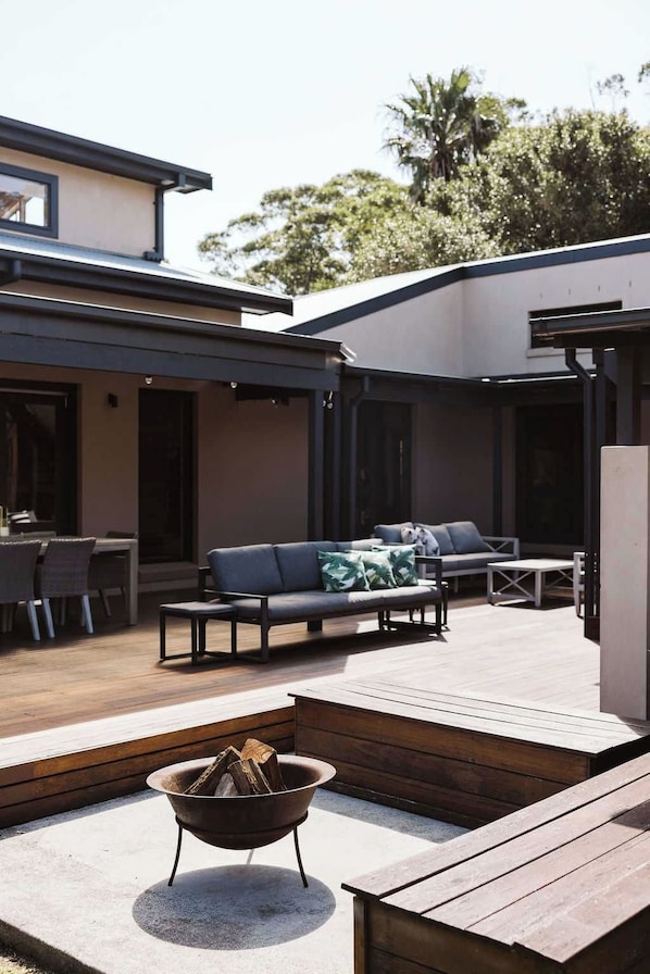 An outdoor patio area with a fire pit, seating, and a dining table. - The Agave (Currarong)