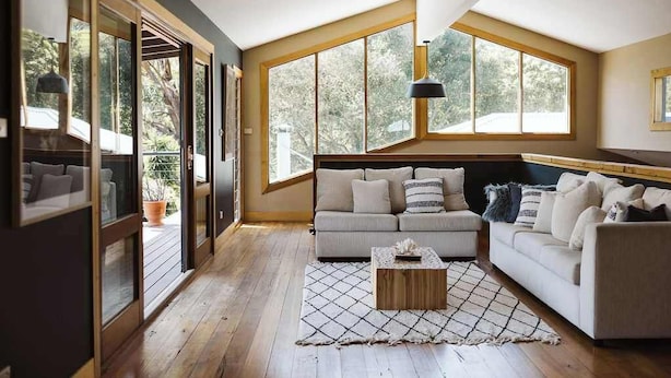 Un salon spacieux avec un grand canapé, une table basse et une vue sur l’extérieur grâce à de grandes fenêtres.