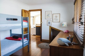 A bunk bed room with a desk, a lamp, and framed pictures on the wall. - The Agave (Currarong)