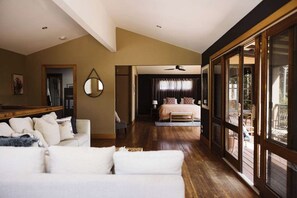 A spacious living room with a large sofa, a dining area, and a bedroom with a large window. - The Agave (Currarong)