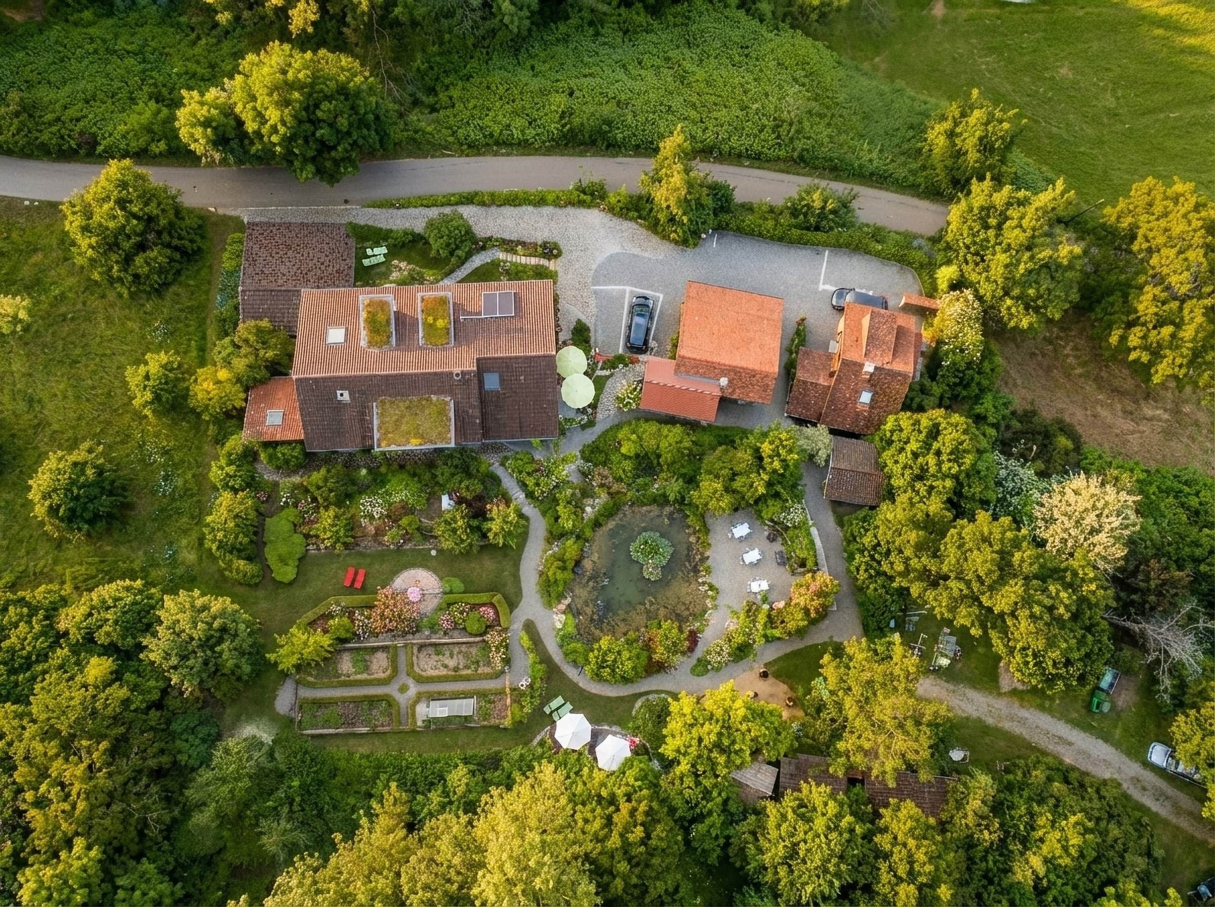 Vue aérienne d’un quartier résidentiel avec de nombreuses maisons, une allée pavée et de la végétation environnante.