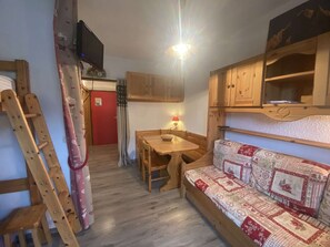 A cozy room with a wooden table, a bench, a TV, and a red door. - Renovated Cozy Apartment for 4-5 People with Pool Access (Arêches-Beaufort)